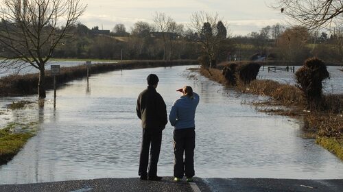 Two people stood looking at flooded road in UK