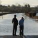 Two people stood looking at flooded road in UK