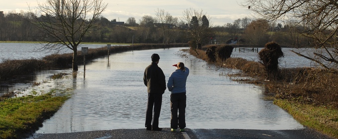 Two people stood looking at flooded road in UK